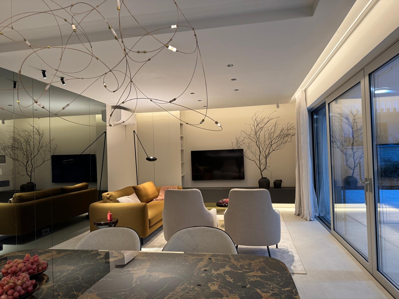 A photorealistic close-up of a luxurious condominium kitchen. Focus on the high-end appliances, marble countertops, and custom cabinetry. The lighting is warm and inviting. Include elements like fresh flowers and gourmet food to convey a sense of luxury. The camera angle is a close-up, capturing the intricate details of the kitchen. 4k resolution.